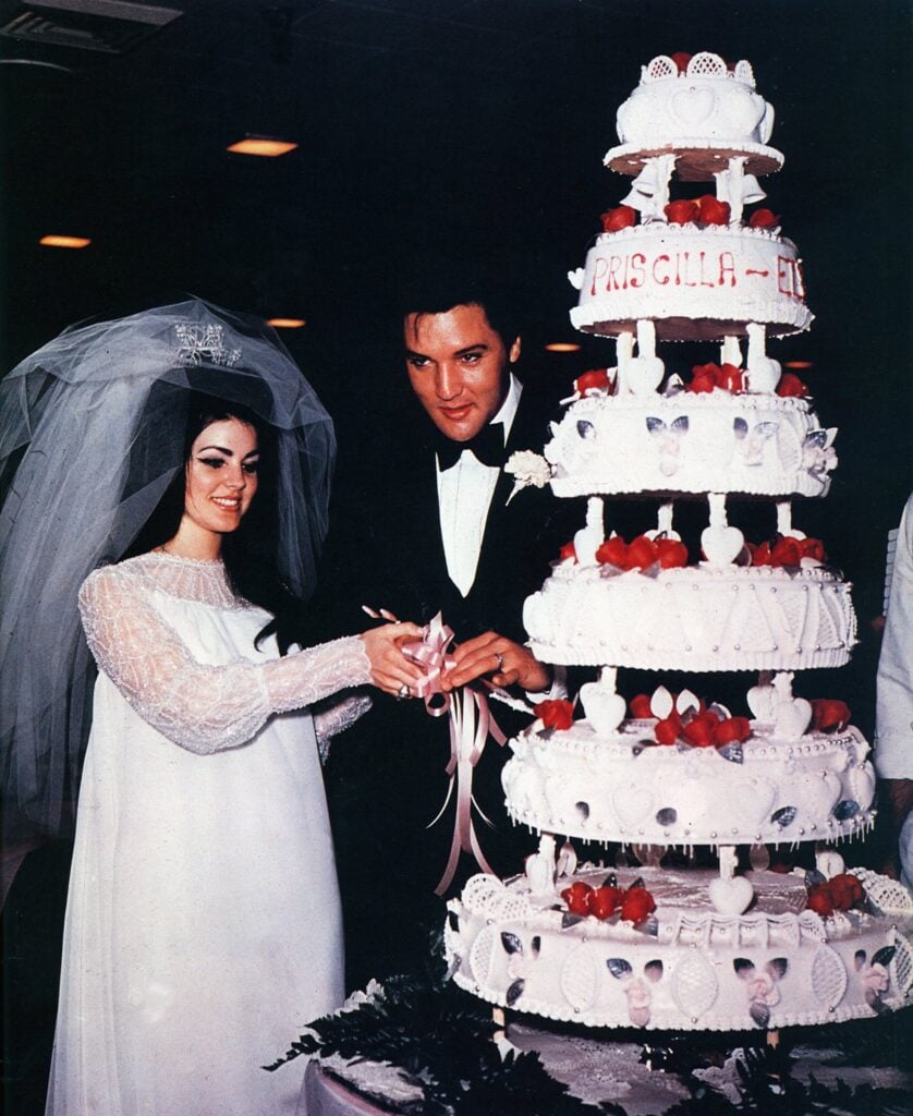 Photo of Priscilla PRESLEY and Elvis PRESLEY standing next to their wedding cake