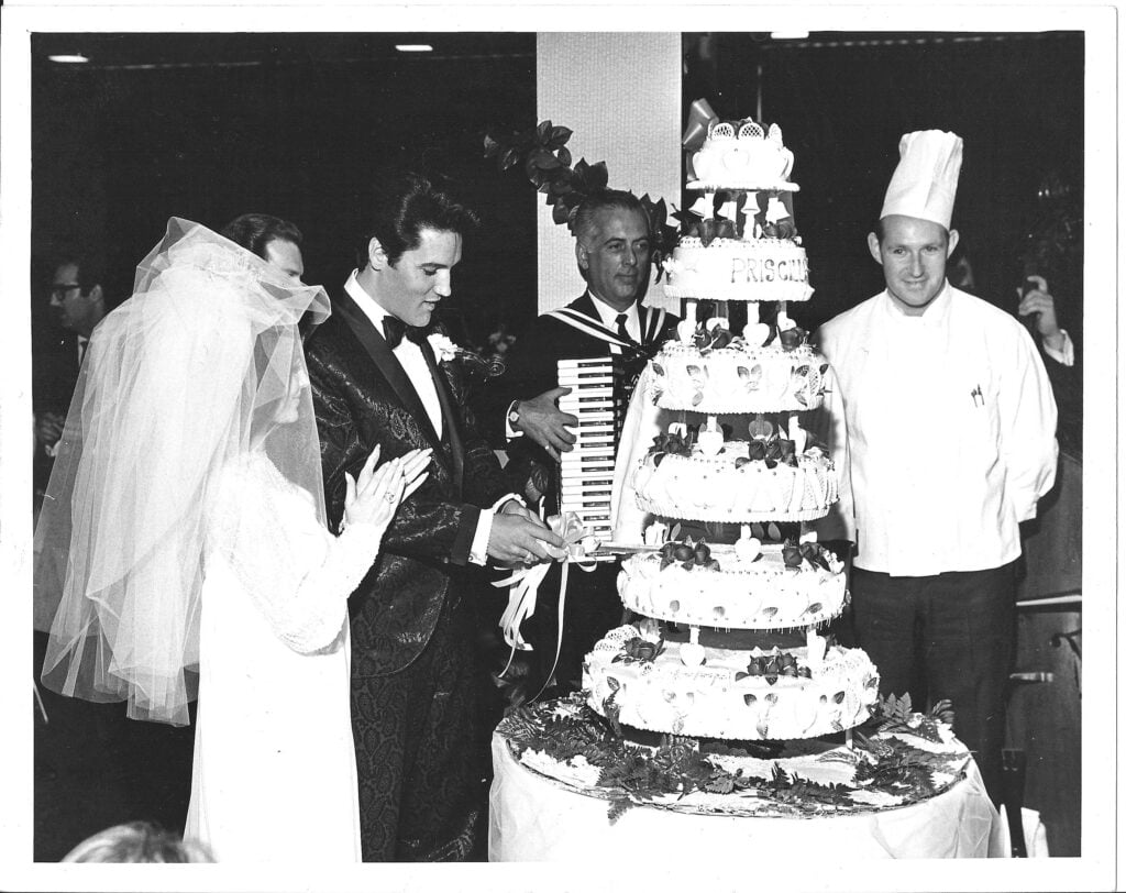elvis and priscilla presley standing in front of their wedding cake